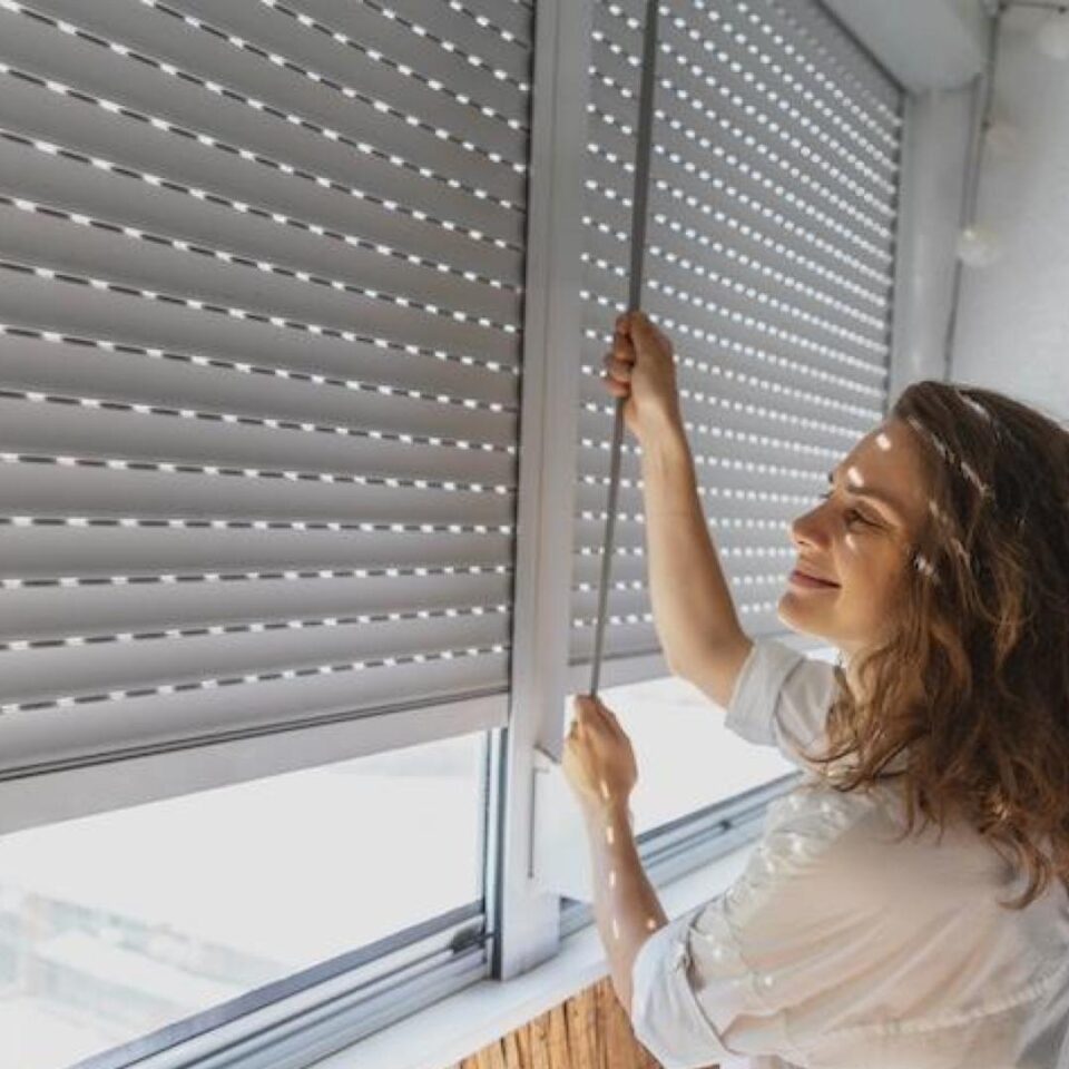 ragazza felice solleva una tapparella bianca